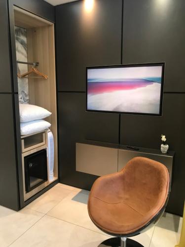 salon z krzesłem i telewizorem z płaskim ekranem w obiekcie Le Duke w mieście Uzès