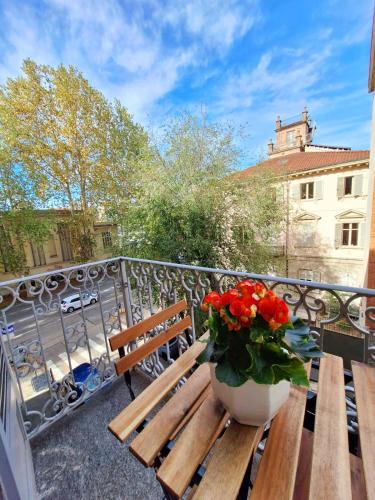 a wooden bench on a balcony with a vase of flowers at Casa Salvia in Turin