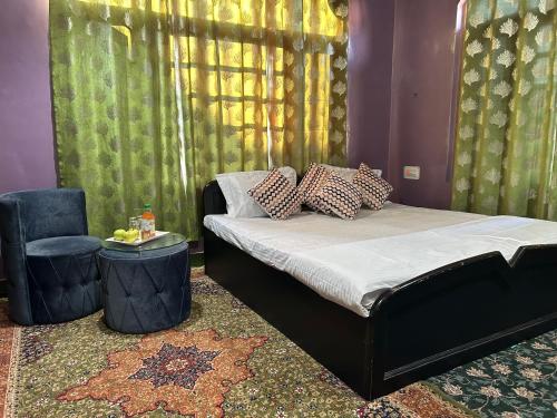a bedroom with a bed and a chair and curtains at The Local B&B in Srinagar
