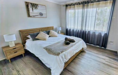 a bedroom with a bed and a large window at Twin Palms @ The Basin in St Georges Basin