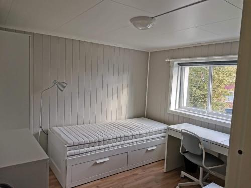 a bedroom with a bed and a desk and a window at Room with shared kitchen and bathroom nr 2 in Tromsø