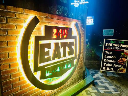 a sign on a brick wall with a lit up eat sign at 240 - Two forty in Bandarawela