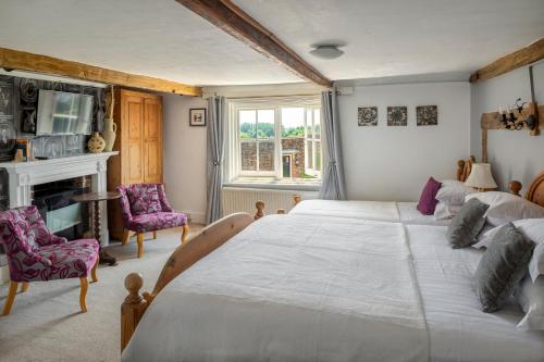 a bedroom with a large white bed and a fireplace at The Hope Anchor in Rye