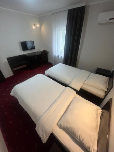 a hotel room with two beds and a television at Hotel Elegance in Belgrade