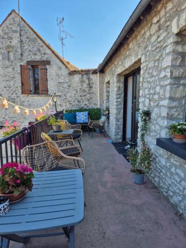 a patio with blue tables and chairs and a building at l'Eden caché in Beaune-la-Rolande