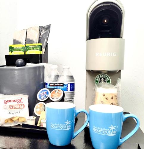 two blue coffee mugs sitting next to a coffee maker at Ocean Sands Beach Boutique Inn-1 Acre Private Beach-St Augustine Historic-2 Miles-Shuttle with Downtown Tour-HEATED Salt Water Pool until 420AM-Popcorn-Cookies-New 4k USD Black Beds- 69 Item Breakfast-Eggs-Bacon-Starbucks- Free Laundry- #904-799-SAND in Saint Augustine