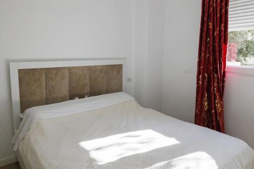a white bed with a red curtain and a window at SAB 1 Cozy Modern Apartment Fier in Fier
