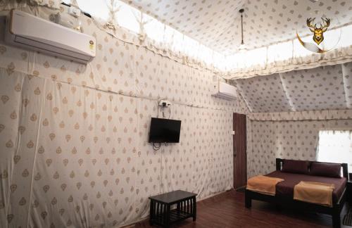 a bedroom with a bed and a tv on the wall at Woods Creek in Dandeli