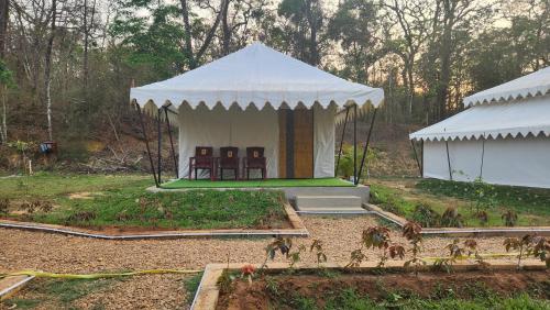 a white tent with two chairs in a garden at Woods Creek in Dandeli