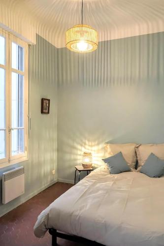 - une chambre avec un grand lit blanc et un lustre dans l'établissement CHARTREUX - Gare St Charles - Vieux port, à Marseille