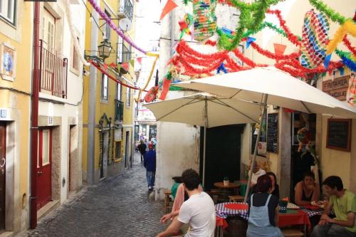 a group of people sitting in an alley with umbrellas at Sweet Alfama, Apartment 1 in Lisbon