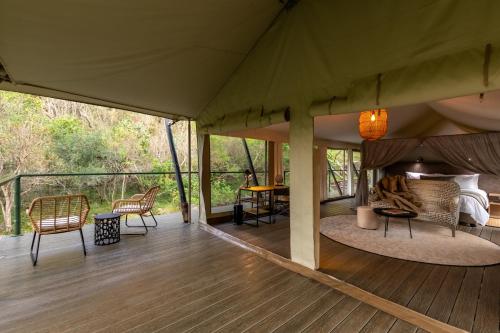 a tent with a bed and chairs on a deck at Mbizane Escarpment Retreat in Schoemanskloof
