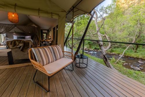 a room with a chair on a deck with a view of a river at Mbizane Escarpment Retreat in Schoemanskloof
