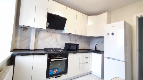 a kitchen with white cabinets and a stove top oven at Партизанська 23 CityRooms in Bila Tserkva