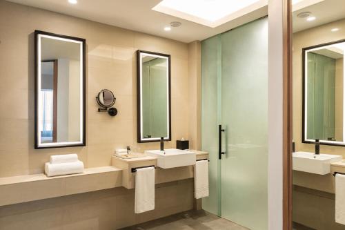 a bathroom with two sinks and two mirrors at Sheraton Mall of the Emirates Hotel, Dubai in Dubai
