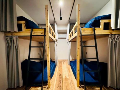 two bunk beds in a room with blue beds at ゲストハウスSLOW HOUSE okuizumo in Minarimachi