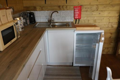 a kitchen with a sink and a dishwasher at The Cabin Pipershill in Newtown Butler