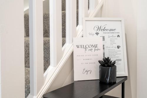 a stairway with a welcome sign on a table at Hemel Apartments - Hemel Haven in Hemel Hempstead