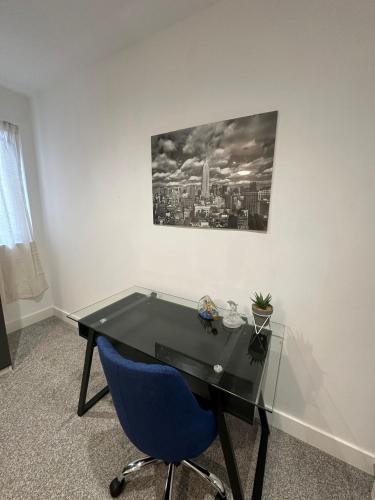 a black desk with a blue chair and a picture on the wall at Hemel Apartments - Hemel Haven in Hemel Hempstead