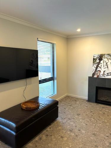 a living room with a black leather couch and a fireplace at Versatile summer beach house or cosy winter retreat! in Mandurah