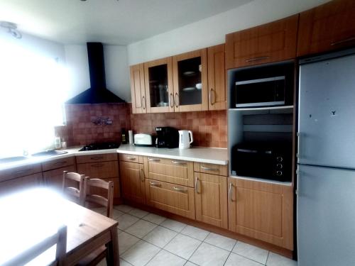 une cuisine avec des armoires en bois et un réfrigérateur noir dans l'établissement Family apartment near Paris, à Alfortville