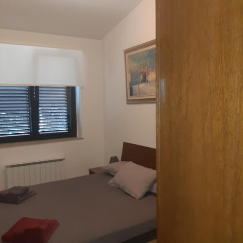 a small bedroom with a bed and a window at APARTMA ERNESTINO in Portorož