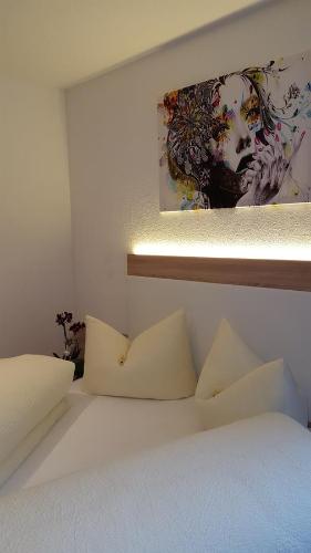 Una cama blanca con almohadas y un cuadro en la pared. en Apart La Vita, en Kappl