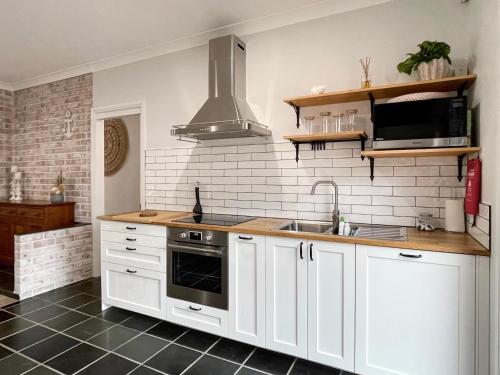 a kitchen with white cabinets and a sink at 7Palms Retreat at Jervis Bay in Vincentia