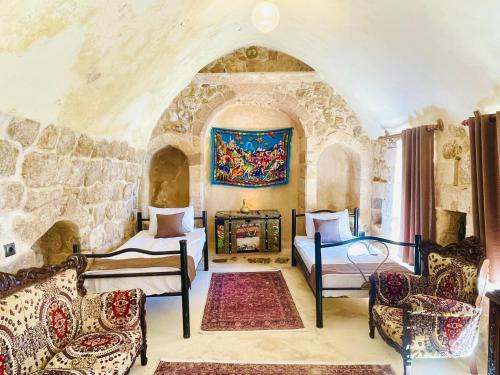 une chambre avec deux lits et un tableau au mur dans l'établissement ŞEHRAZAD OTEL MERDİN masal şehri konağı, à Mardin