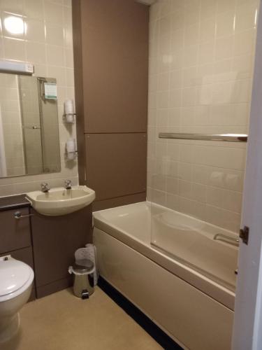a bathroom with a tub and a sink and a toilet at Sandown Park Lodge in Esher