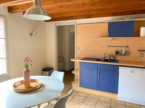 une cuisine avec une table blanche et des armoires bleues dans l'établissement Le logis de la Forge à 10 min du Puy duFou, à Mortagne-sur-Sèvre