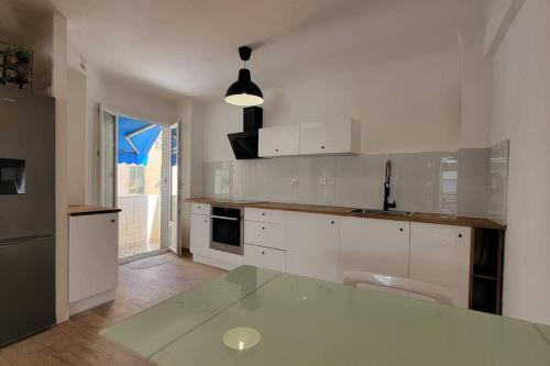 une cuisine avec des placards blancs et un comptoir en verre dans l'établissement Apartment 3 pieces par la mer avec climatisation, à Nice