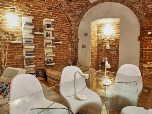 a room with white chairs and a brick wall at La Canonica di Soglio in Camerano Casasco