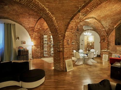 a living room with brick walls and white chairs at La Canonica di Soglio in Camerano Casasco