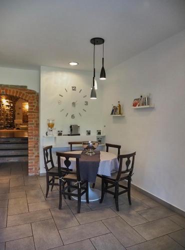 a dining room with a table and chairs and a clock at La Canonica di Soglio in Camerano Casasco