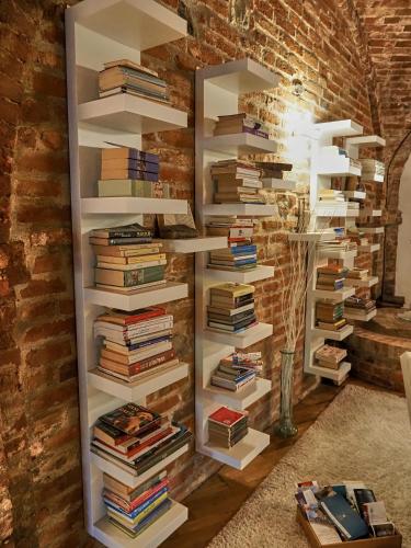 a book shelf filled with books against a brick wall at La Canonica di Soglio in Camerano Casasco