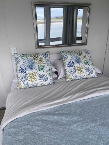 a bed with blue and white pillows and a window at Moonshine in Hermanus