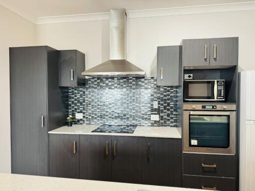 a kitchen with gray cabinets and a stove top oven at Peaceful Share Suite in Coopers Plains in Brisbane