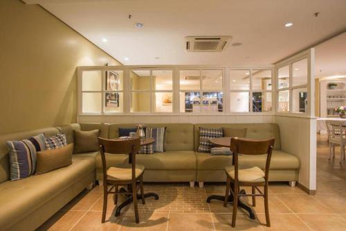 a living room with a couch and a table and chairs at Suíte premium nº 104 no Hotel Metropolitan in Bauru