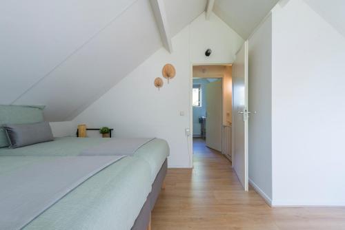 Cozy No 2 Wellness Villa Hottub, Sauna en houtkachel في Hernen: غرفة نوم بيضاء مع سرير وممر