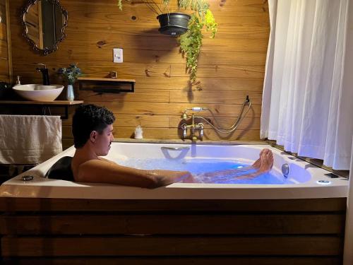 a man sitting in a bath tub at O Chalé Encantado - Rancho Queimado in Rancho Queimado