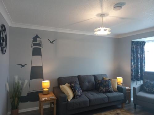 a living room with a couch and a lighthouse on the wall at Meadow Crest in Great Yarmouth