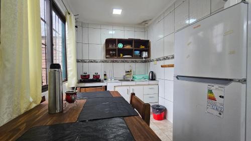een keuken met een tafel en een witte koelkast bij Cómodo Dúplex en Puerto Iguazú in Puerto Iguazú