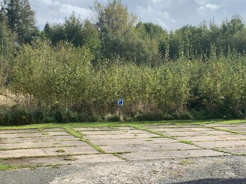 a parking lot with a blue sign in front of a field at Apartmán Stará cihelna in Klatovy