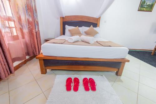 a bedroom with a bed with red shoes on it at Almasi in Ukunda