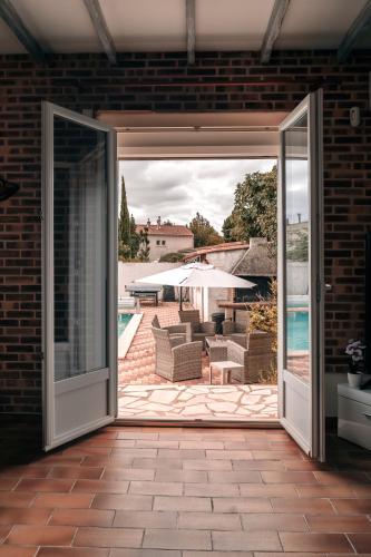 an open door to a patio with a pool at Villa Terra Mera piscine privée proche de Narbonne in Cuxac-dʼAude