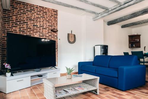 a living room with a blue couch and a tv at Villa Terra Mera piscine privée proche de Narbonne in Cuxac-dʼAude
