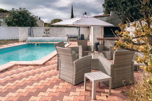 a group of chairs and an umbrella next to a pool at Villa Terra Mera piscine privée proche de Narbonne in Cuxac-dʼAude