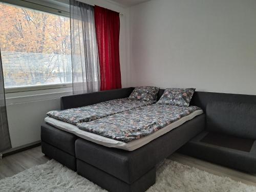 a couch with a futon in a room with a window at City Apartment Hilla in Rovaniemi