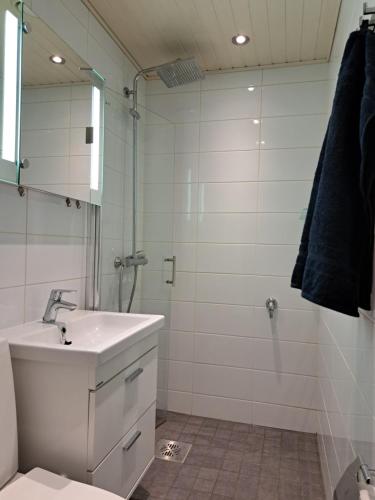 a white bathroom with a sink and a shower at City Apartment Hilla in Rovaniemi